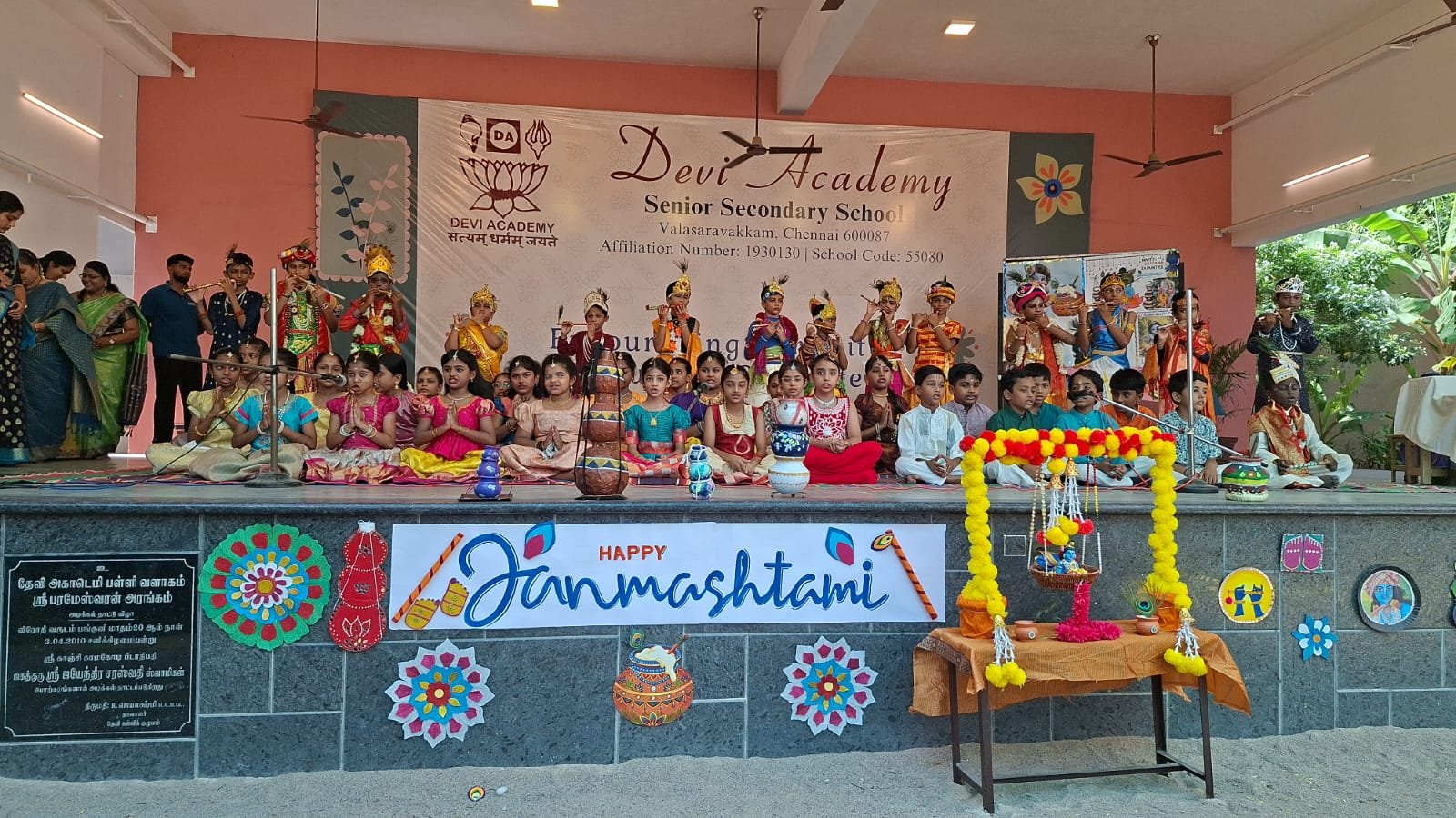 Students in Krishna and Radha costumes on stage for Janmashtami at Devi Academy